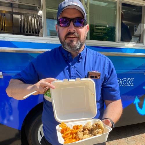 Man holding a to go container of wings and fries